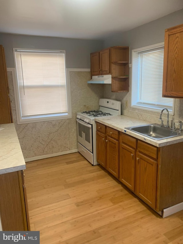 kitchen with gas range gas stove, sink, a healthy amount of sunlight, and light hardwood / wood-style flooring