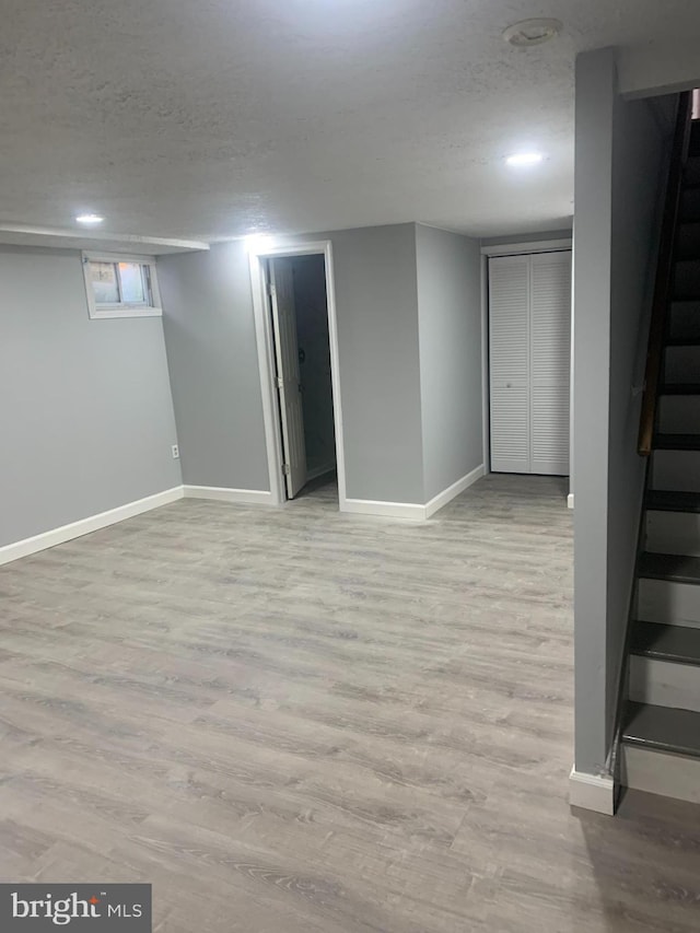 basement with a textured ceiling and light hardwood / wood-style flooring