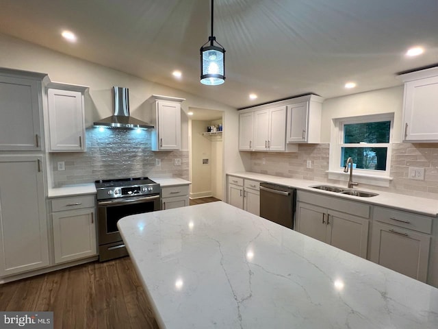 kitchen featuring appliances with stainless steel finishes, backsplash, wall chimney exhaust hood, sink, and dark hardwood / wood-style floors