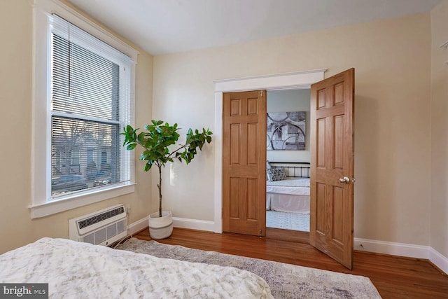 bedroom with a wall mounted air conditioner, wood-type flooring, and heating unit