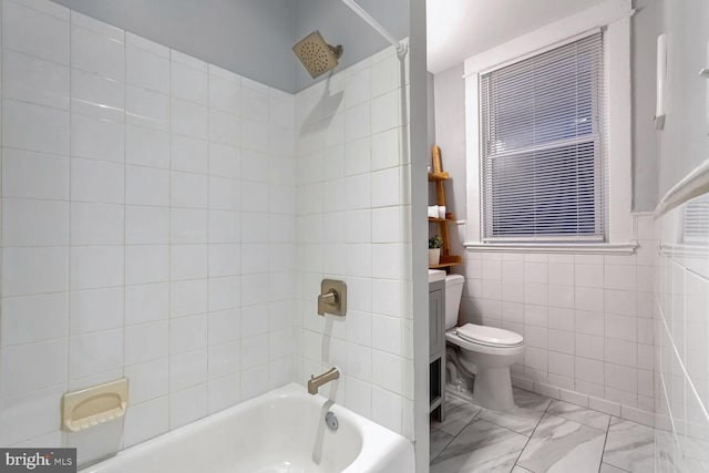 full bathroom featuring tiled shower / bath, vanity, toilet, and tile walls