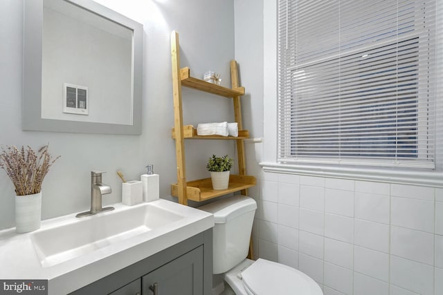 bathroom with vanity, tile walls, and toilet