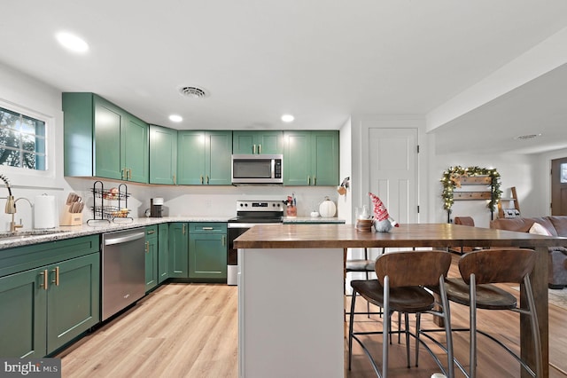 kitchen with wood counters, sink, stainless steel appliances, and green cabinetry