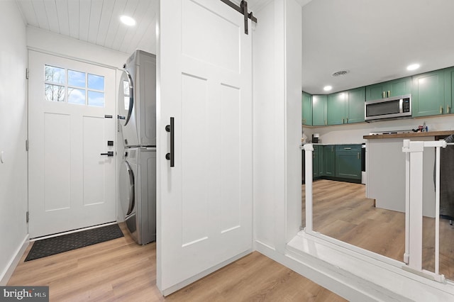 interior space with a barn door, stacked washing maching and dryer, and light hardwood / wood-style floors