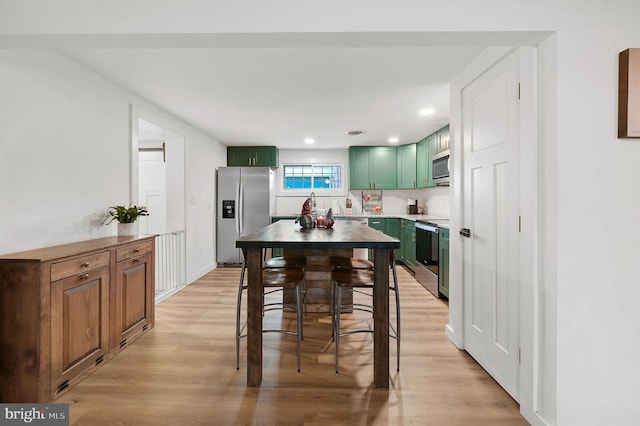 kitchen featuring light wood-type flooring, stainless steel appliances, and green cabinetry