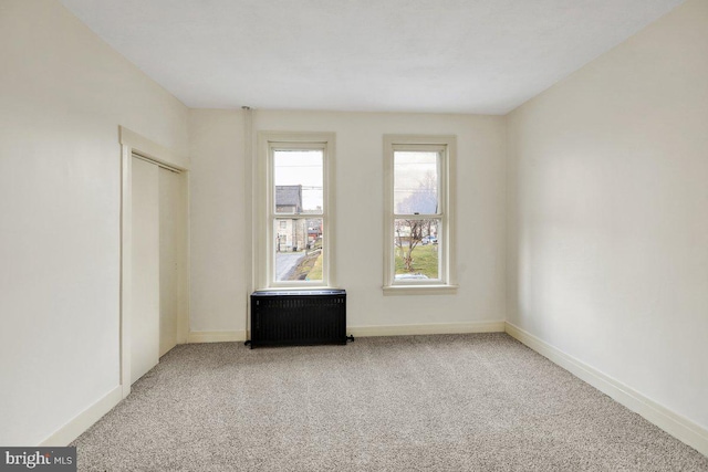 unfurnished bedroom with carpet, radiator heating unit, and a closet