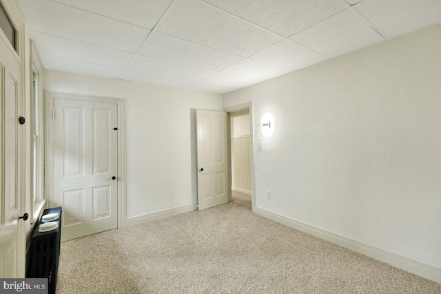 unfurnished bedroom with light carpet and a drop ceiling