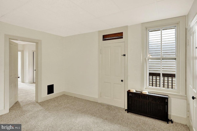 carpeted empty room with radiator heating unit