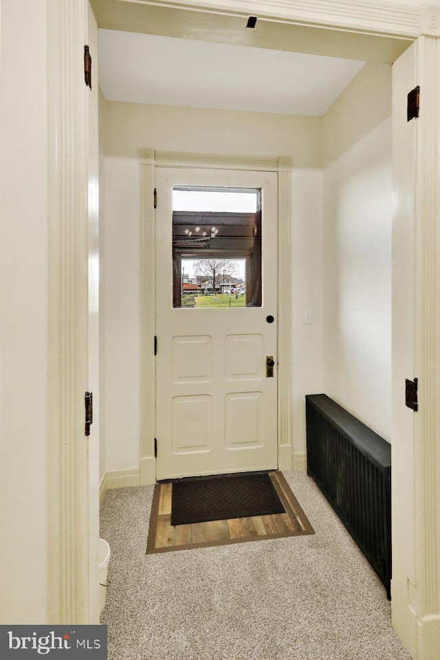 doorway to outside with light colored carpet and radiator heating unit