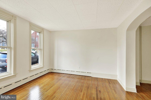 empty room with baseboard heating and hardwood / wood-style floors