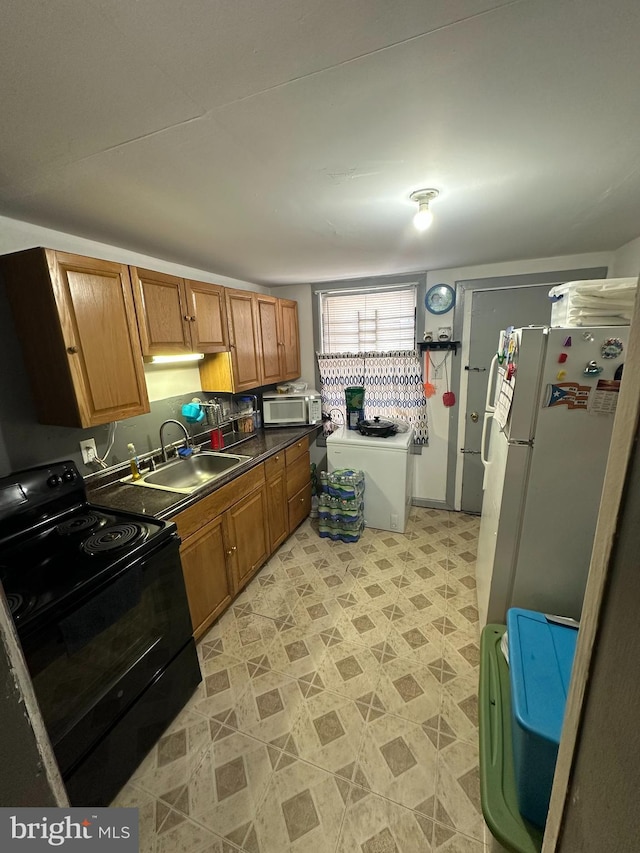 kitchen featuring black / electric stove, sink, and white fridge