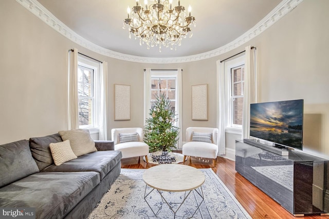 living room with a notable chandelier, wood-type flooring, and crown molding