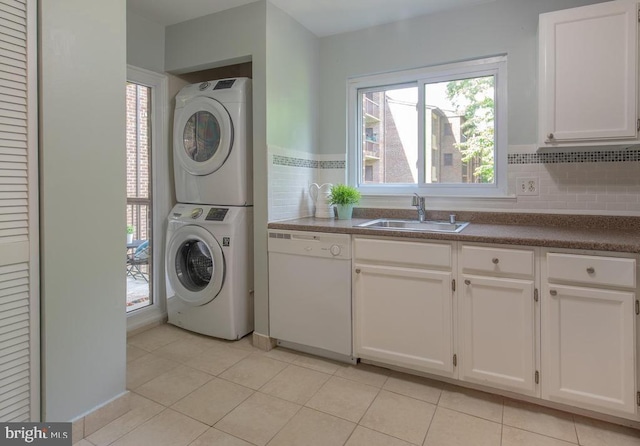 clothes washing area featuring sink, light tile patterned floors, and stacked washing maching and dryer