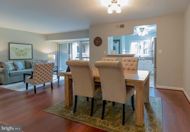 dining room featuring a wealth of natural light, stacked washer and dryer, and dark hardwood / wood-style floors