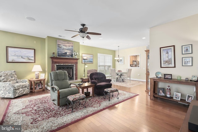 living room with ceiling fan with notable chandelier and hardwood / wood-style floors