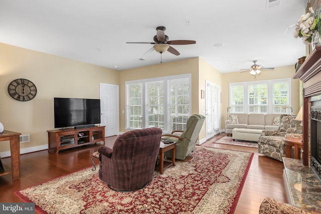 living room featuring ceiling fan, a high end fireplace, and dark wood-type flooring