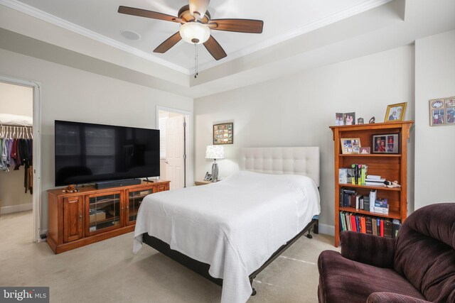 bedroom featuring ceiling fan, light colored carpet, a tray ceiling, ornamental molding, and a closet