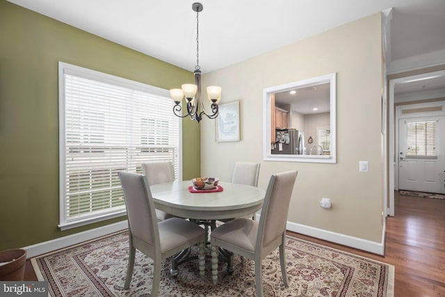 dining area with hardwood / wood-style flooring, an inviting chandelier, and plenty of natural light