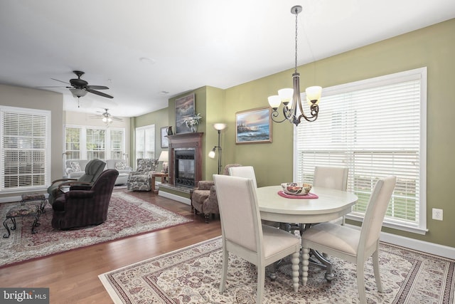 dining room featuring ceiling fan with notable chandelier and hardwood / wood-style flooring