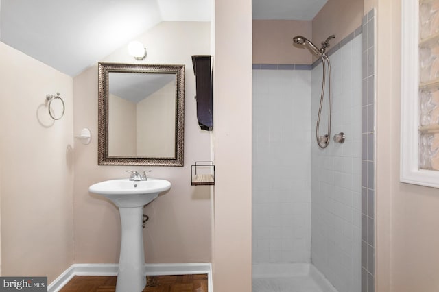 bathroom with tiled shower and vaulted ceiling