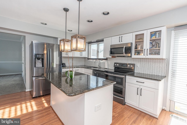 kitchen featuring a center island, white cabinetry, light hardwood / wood-style flooring, hanging light fixtures, and appliances with stainless steel finishes