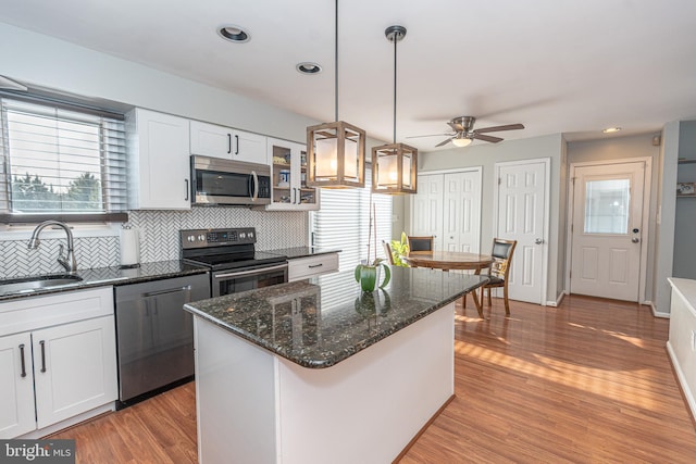 kitchen with white cabinetry, appliances with stainless steel finishes, a kitchen island, pendant lighting, and sink