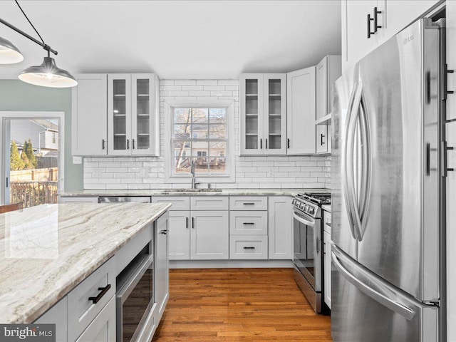 kitchen featuring white cabinets, sink, light stone countertops, decorative light fixtures, and stainless steel appliances