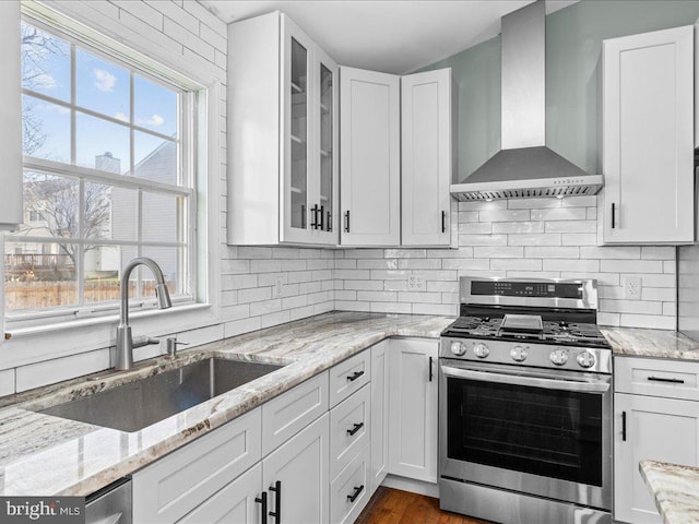 kitchen with white cabinetry, sink, wall chimney range hood, and stainless steel range with gas stovetop