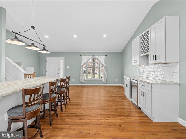 kitchen featuring white cabinets, pendant lighting, light stone countertops, and tasteful backsplash