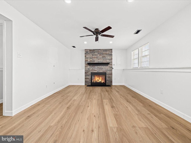 unfurnished living room featuring a stone fireplace, ceiling fan, and light hardwood / wood-style floors