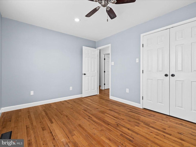 unfurnished bedroom featuring ceiling fan, a closet, and wood-type flooring