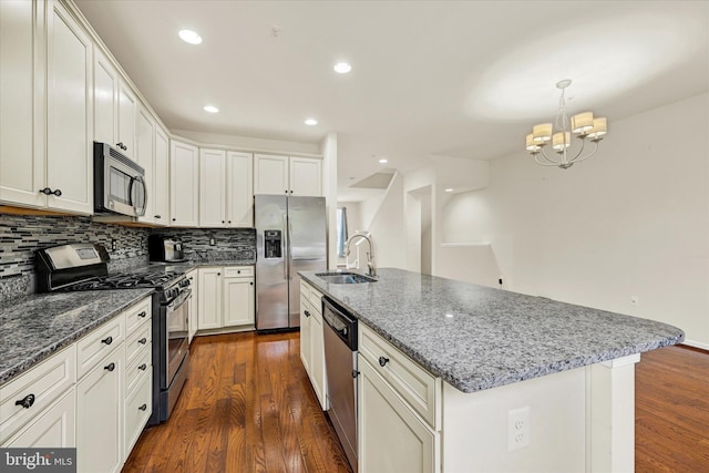 kitchen featuring dark hardwood / wood-style floors, pendant lighting, sink, an island with sink, and stainless steel appliances