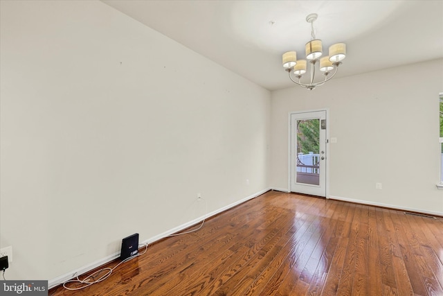 spare room with a notable chandelier and hardwood / wood-style flooring