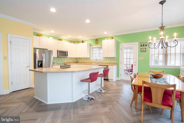 kitchen with white cabinets, a kitchen island, dark parquet flooring, and appliances with stainless steel finishes