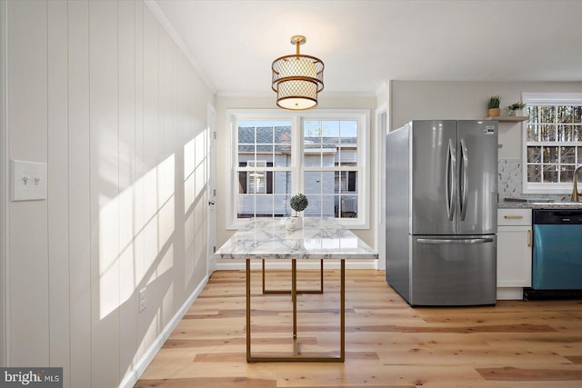 kitchen with appliances with stainless steel finishes, light stone counters, white cabinetry, and light hardwood / wood-style flooring