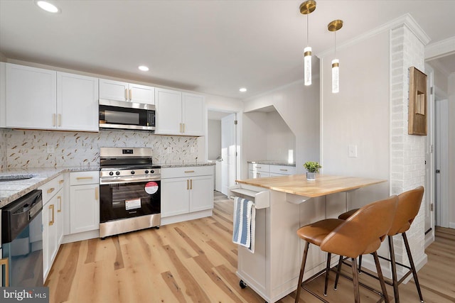 kitchen featuring a kitchen breakfast bar, appliances with stainless steel finishes, white cabinetry, and light stone counters