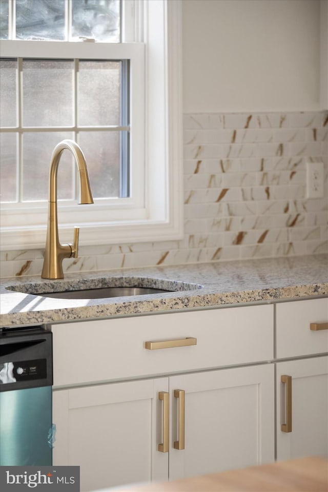 room details featuring light stone countertops, sink, white cabinets, and dishwasher