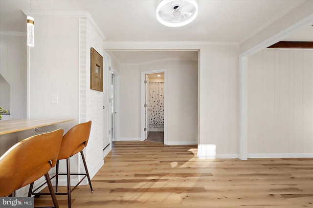 dining space with light wood-type flooring and ornamental molding