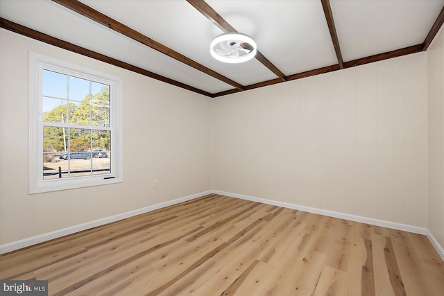 spare room featuring light hardwood / wood-style floors and beamed ceiling