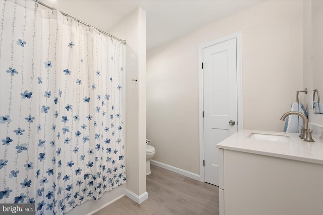 bathroom featuring toilet, hardwood / wood-style flooring, walk in shower, and vanity