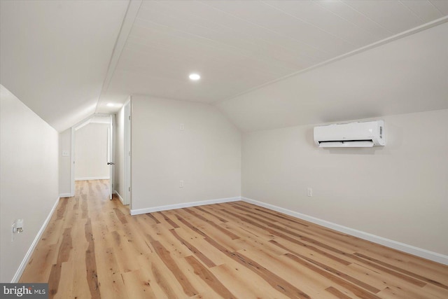 bonus room featuring vaulted ceiling, light hardwood / wood-style flooring, and a wall mounted air conditioner