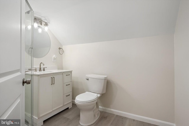 bathroom with vaulted ceiling, toilet, hardwood / wood-style floors, and vanity