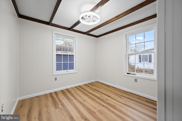 spare room featuring beam ceiling and light wood-type flooring