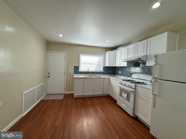 kitchen featuring white appliances, dark wood-type flooring, white cabinets, sink, and decorative backsplash