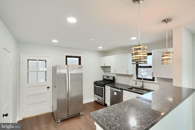 kitchen with sink, decorative light fixtures, white cabinets, kitchen peninsula, and appliances with stainless steel finishes