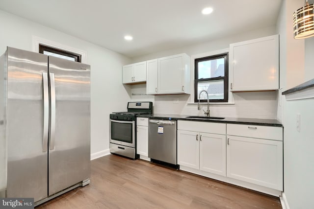 kitchen with light hardwood / wood-style floors, decorative backsplash, white cabinets, appliances with stainless steel finishes, and sink