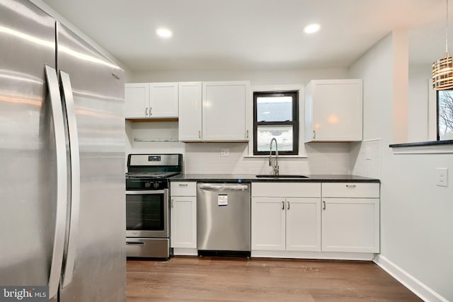 kitchen featuring sink, white cabinets, tasteful backsplash, light hardwood / wood-style flooring, and appliances with stainless steel finishes