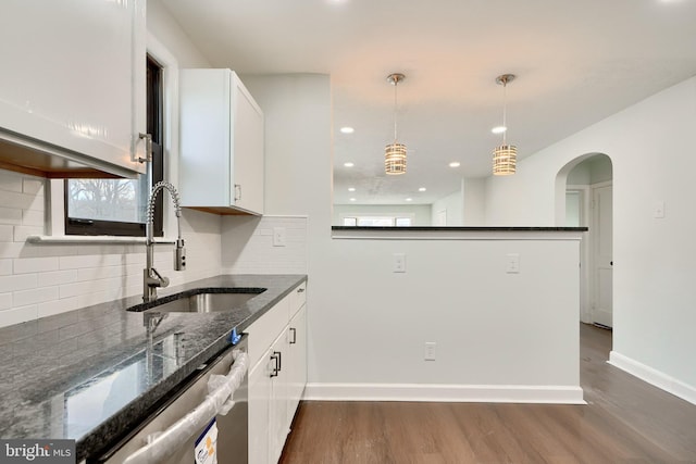 kitchen with dishwasher, dark stone countertops, sink, white cabinetry, and decorative light fixtures