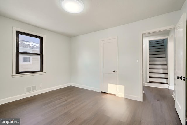 unfurnished bedroom with dark wood-type flooring and a closet