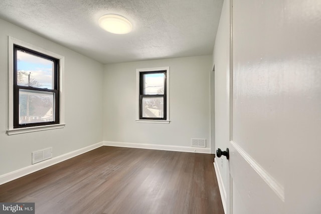 empty room with a textured ceiling and dark hardwood / wood-style flooring